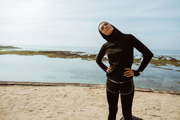 Foto giovane donna musulmana in buona salute che si scalda all'aperto