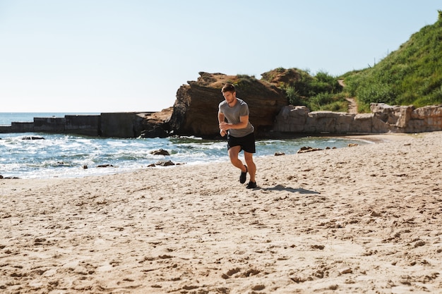 Healthy young sportsman jogging on a sand