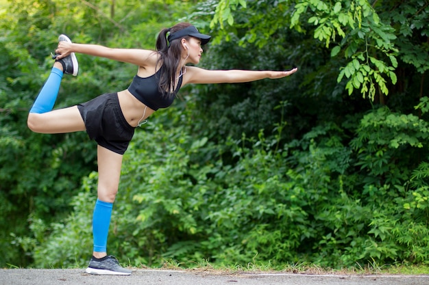 Healthy young woman practicing yoga before running training. Woman doing sports outdoor.