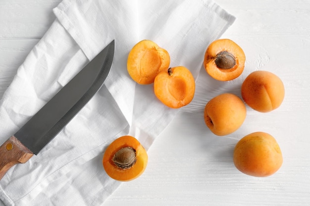 Heap of apricots with knife on table