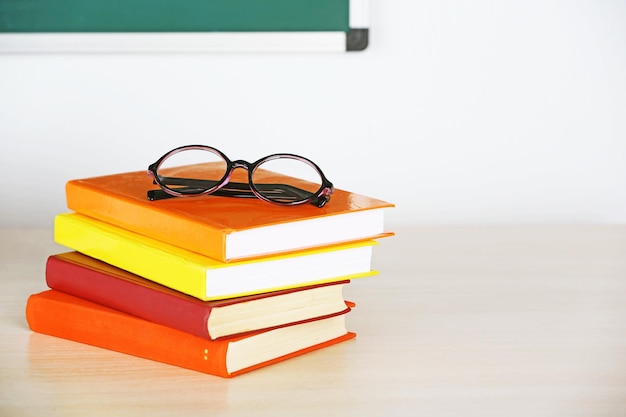 Heap of books and glasses on table in class