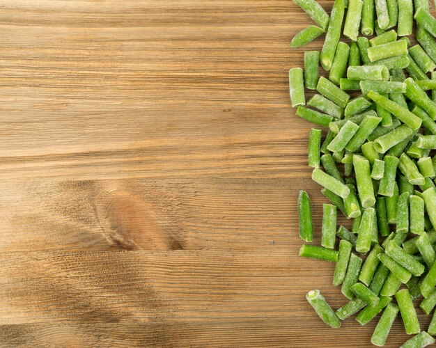 Heap of Chopped Frozen Green Beans on Wood Background