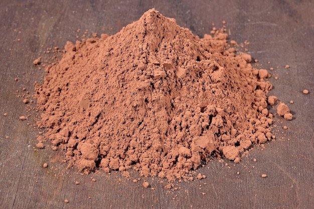 Photo heap of cocoa powder on a wooden background