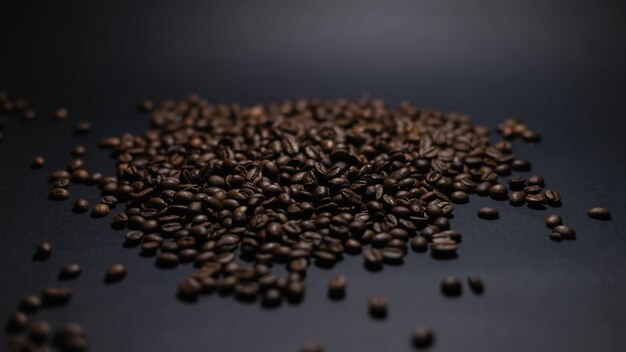 Heap of coffee beans on black background. Coffee beans pile isolated on black background. Culinary coffee background.