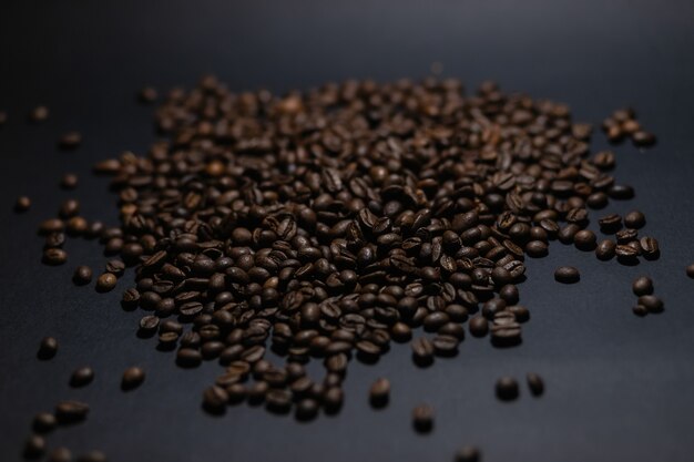Куча кофейных зерен на черном фоне. Куча кофейных зерен, изолированные на черном фоне. Кулинарный кофейный фон.