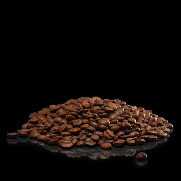 Heap of coffee beans with reflection on black surface