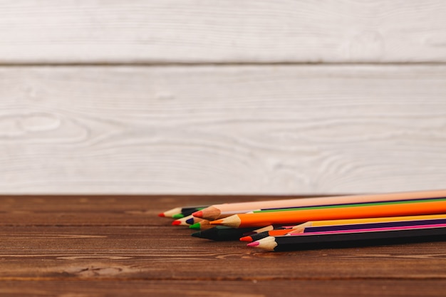 Куча цветных карандашей на деревянном столе, вид спереди