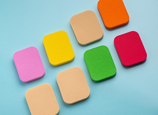 Heap of colorful cosmetic sponges on blue background Top view