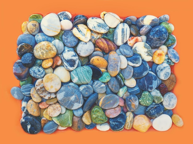 Photo heap of colorful pebbles on orange background