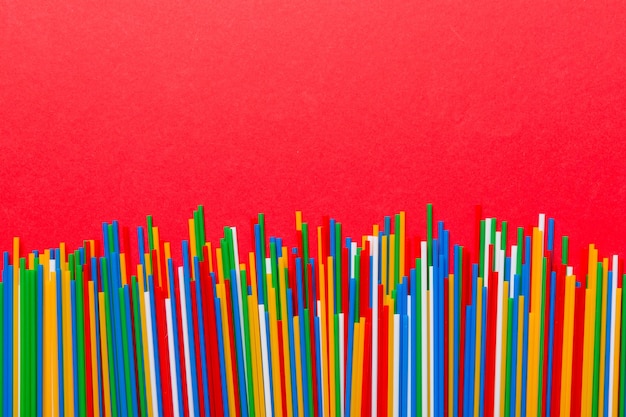 Heap of colorful plastic drinking straws on Colored background flat lay Copy Space for text