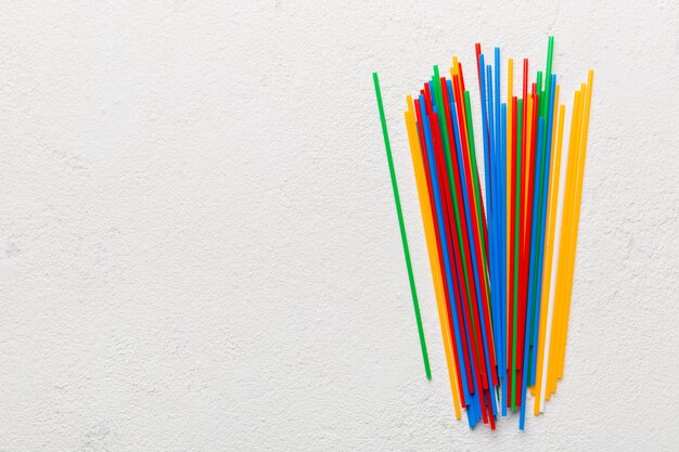 Куча красочных пластиковых соломинок для питья на цветном фоне плоской планировки Copy Space for text