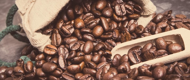 Heap of dark roasted fragrant coffee beans in jute bag