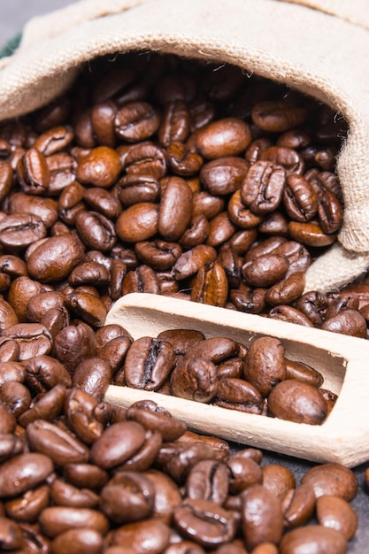 Heap of dark roasted fragrant coffee beans in jute bag