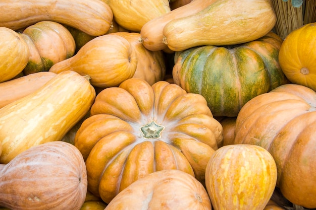 Heap of different shaped pumpkins with hay at the farmers market