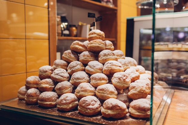 Photo heap of doughnuts on cafe showcase. pile of desserts with sugar powder