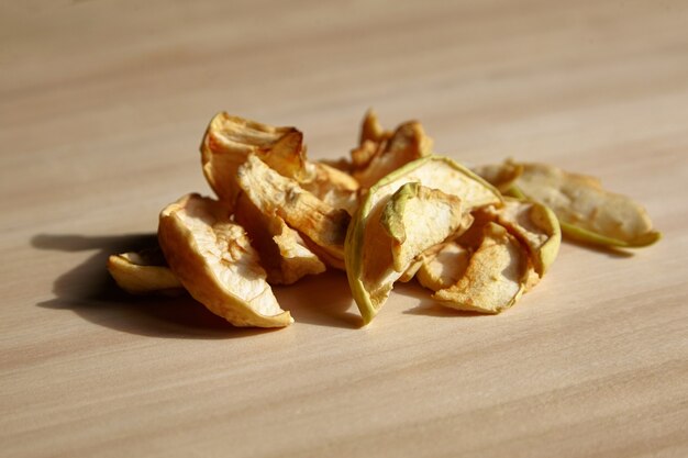 Куча сушеных яблочных ломтиков фруктовых чипсов на деревянном столе