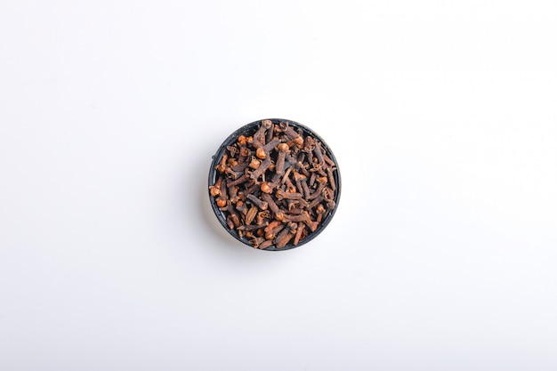 heap of dried cloves in bowl,  on white background