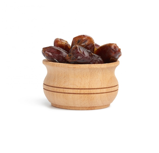 Heap of dried dates in a wooden bowl and isolated on a white background