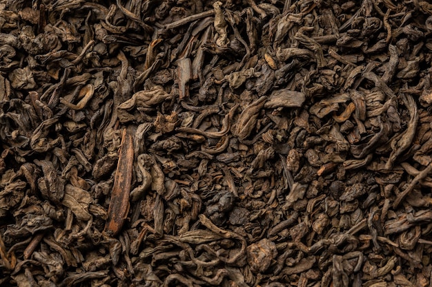 Heap of dry tea leaves. Dried black tea. Textured background of dried leaves of aromatic black tea with cinnamon