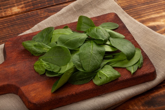 Photo heap of fresh green spinach on the wooden board