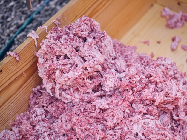Heap of fresh raw ground meat in wooden container in\
abattoir