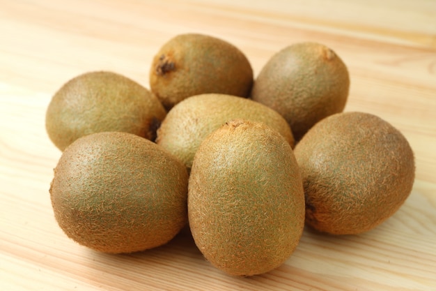 Heap of fresh ripe kiwi whole fruits on wooden table