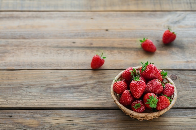 Heap of fresh strawberries in a basket on rustic wooden surface. Healthy eating and diet food concept.