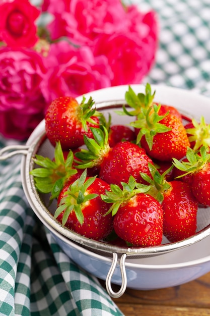 Heap of fresh strawberries in ceramic bowl on rustic