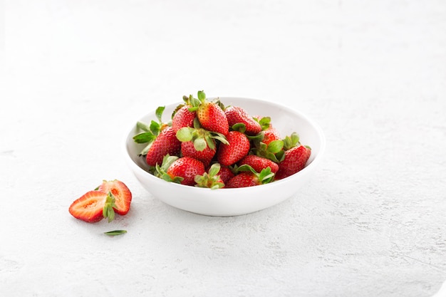 Heap of fresh strawberries in ceramic bowl on white background