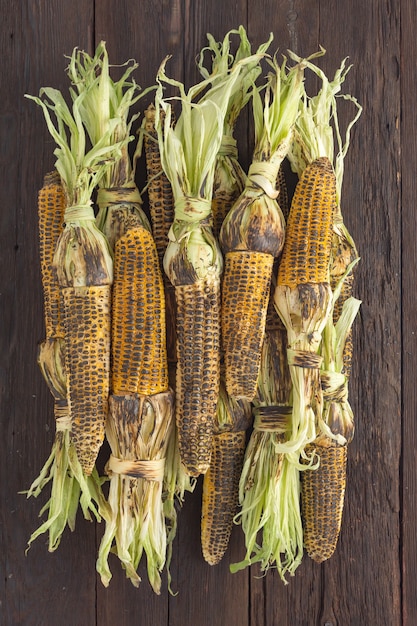 Heap of grilled corn on a wooden table, top view