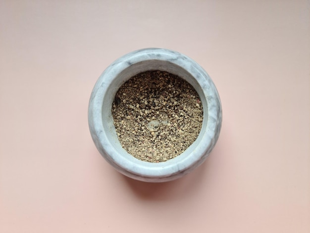 Heap of ground black pepper in gray bowl top view