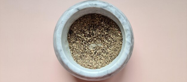 Heap of ground black pepper in gray bowl top view