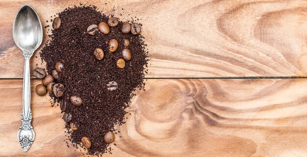 Photo heap of ground coffee and coffee beans with spoon on the table top view space for text