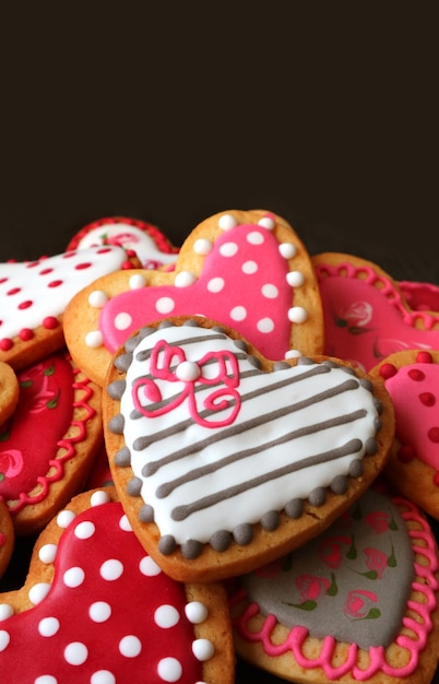 Heap of heart shaped with lovely pattern cookies on black background