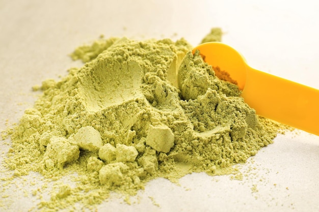 Heap of hemp protein with scoop on table