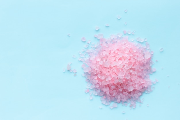 Heap of large sprinkled crystals of pink sea salt closeup on blue