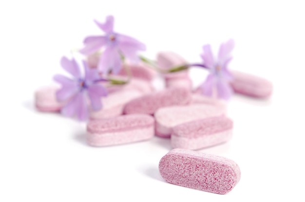 Heap of medicine tablets with flowers isolated on white background