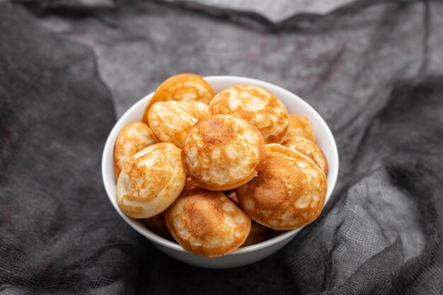 Photo heap of mini cereal pancakes in bowl on bright background