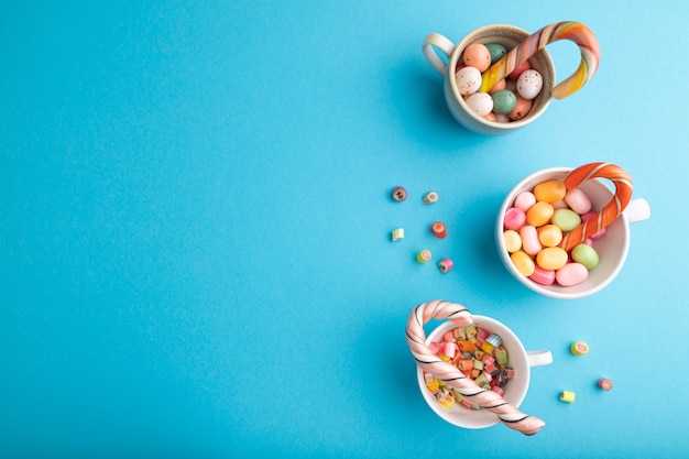 Mucchio di caramelle al caramello multicolori in tazze su pastello blu