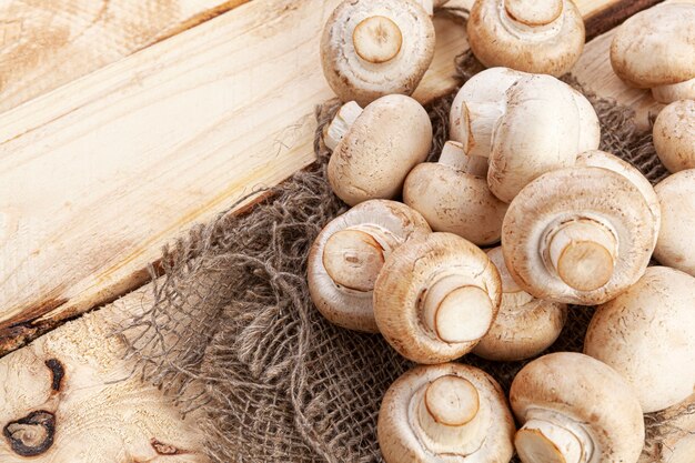 Heap of mushrooms, champignons on old wooden table, top view