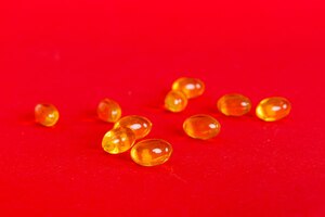 Фото Куча желтых таблеток на цветном фоне таблетки разбросаны по столу куча красных мягких желатиновых капсул концепция витаминов и пищевых добавок