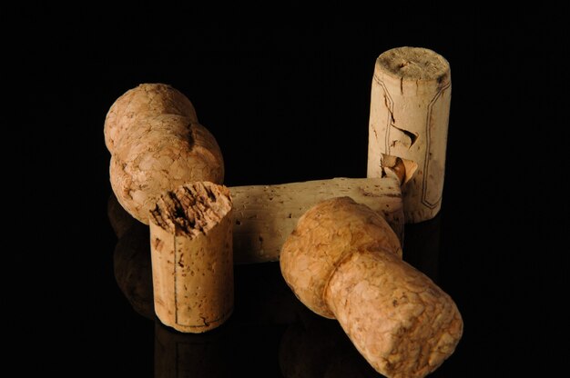 Heap of old wine corks on black background with reflection