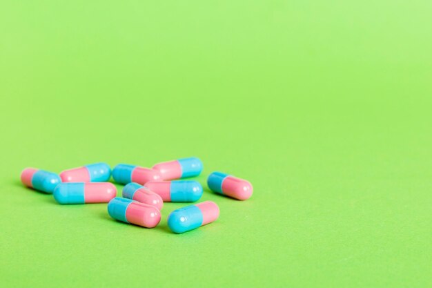 Heap of pink and blue pills on colored background Tablets scattered on a table Pile of red soft gelatin capsule Vitamins and dietary supplements concept