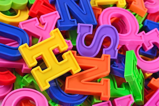 Heap of plastic colored alphabet letters close up as background