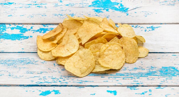 Heap of potato chips on the wooden background