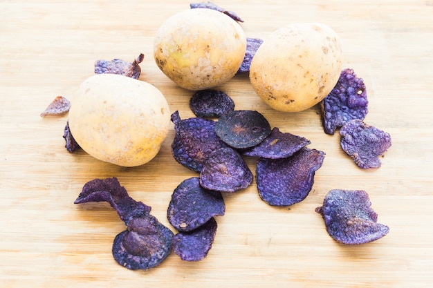 Heap of purple potato chips on wooden background