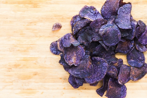 Heap of purple potato chips on wooden background