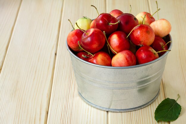 Heap of ranetki in metal bowl on light wooden background