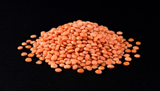 Heap of red lentils isolated on black background