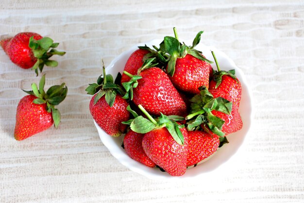 heap of ripe garden strawberries isolated in bowl, topview